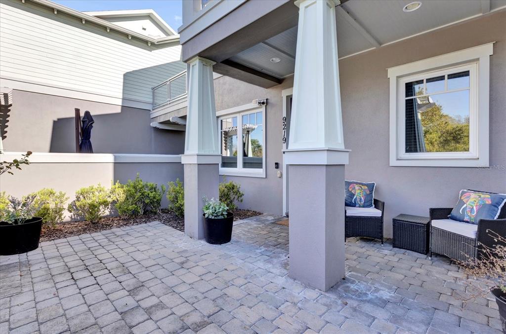 A paved patio area features two large columns, outdoor seating, and a house entrance — 9219 LAUREATE BOULEVARD, ORLANDO, FL