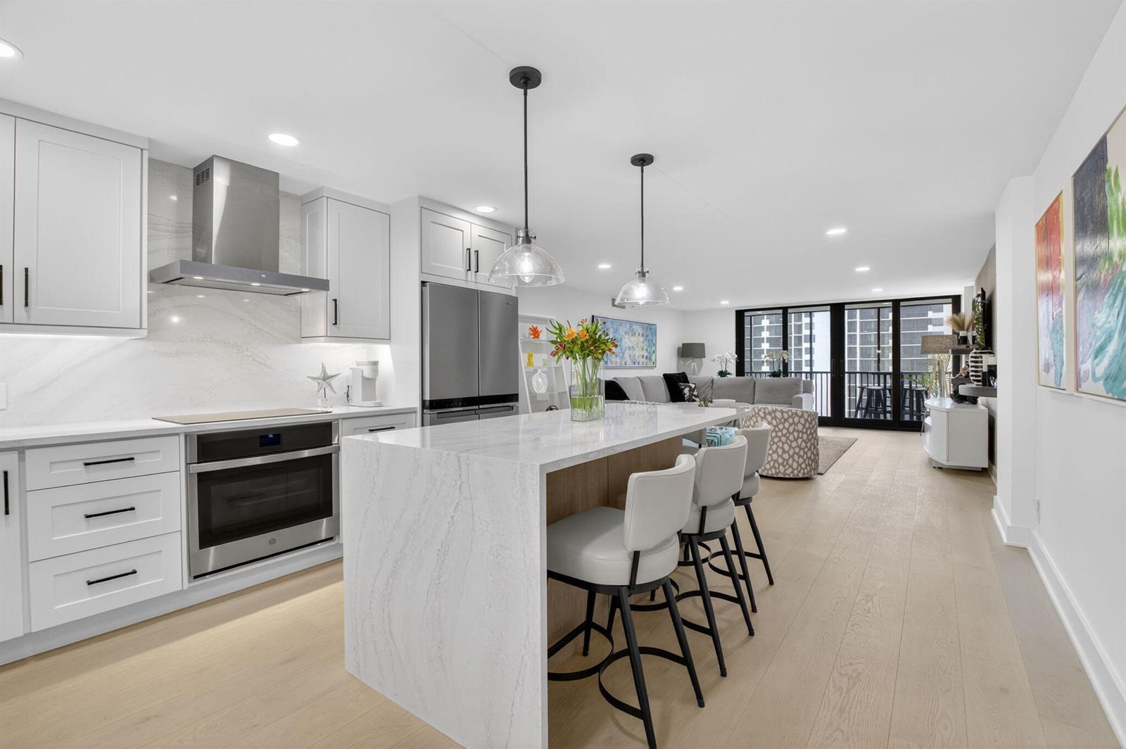 A modern kitchen with a marble island and white cabinetry opens into a living area — 3400 S Ocean Boulevard # 10m, Highland Beach FL 33487, HIGHLAND BEACH, FL