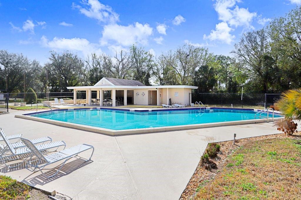 An outdoor swimming pool with a covered patio area and lounge chairs on a sunny day — 2025 SYLVESTER ROAD UNIT C2, LAKELAND, FL