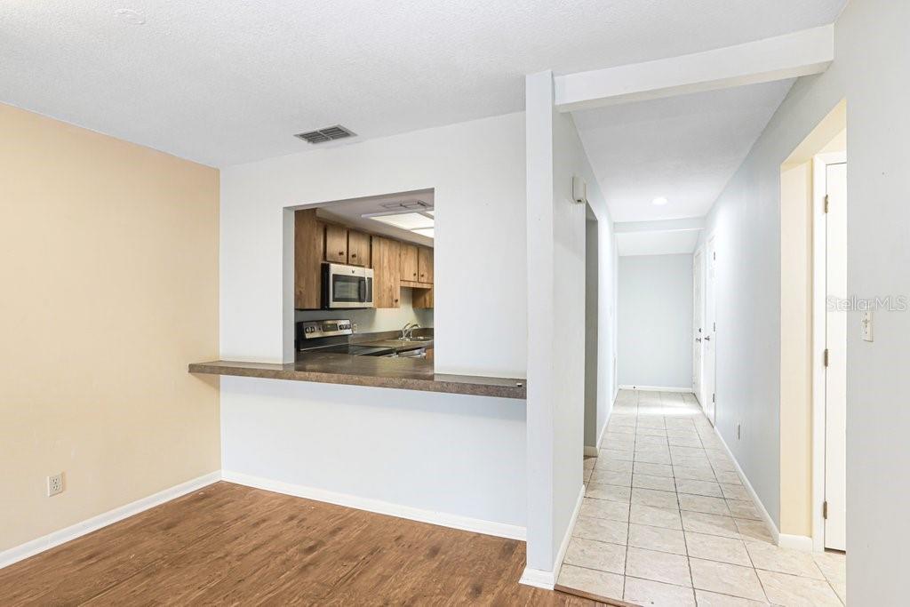 A view from a room with wood-look flooring looking into a kitchen through a pass-through — 2025 SYLVESTER ROAD UNIT C2, LAKELAND, FL