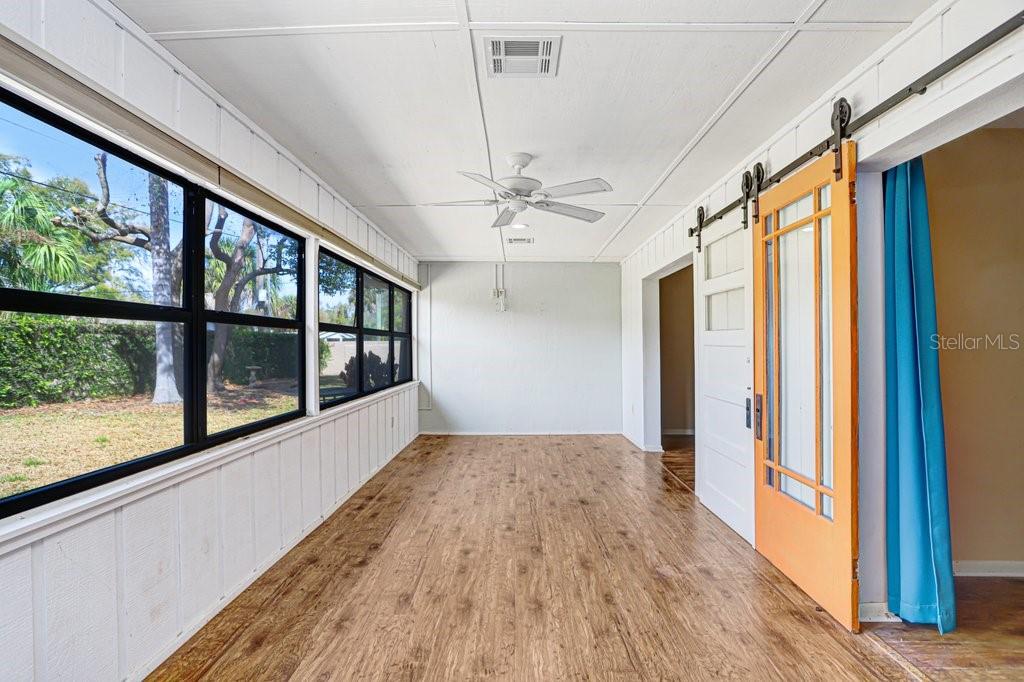 A sunroom features wood-look flooring, a ceiling fan, large windows, and an orange sliding door — 2025 SYLVESTER ROAD UNIT C2, LAKELAND, FL
