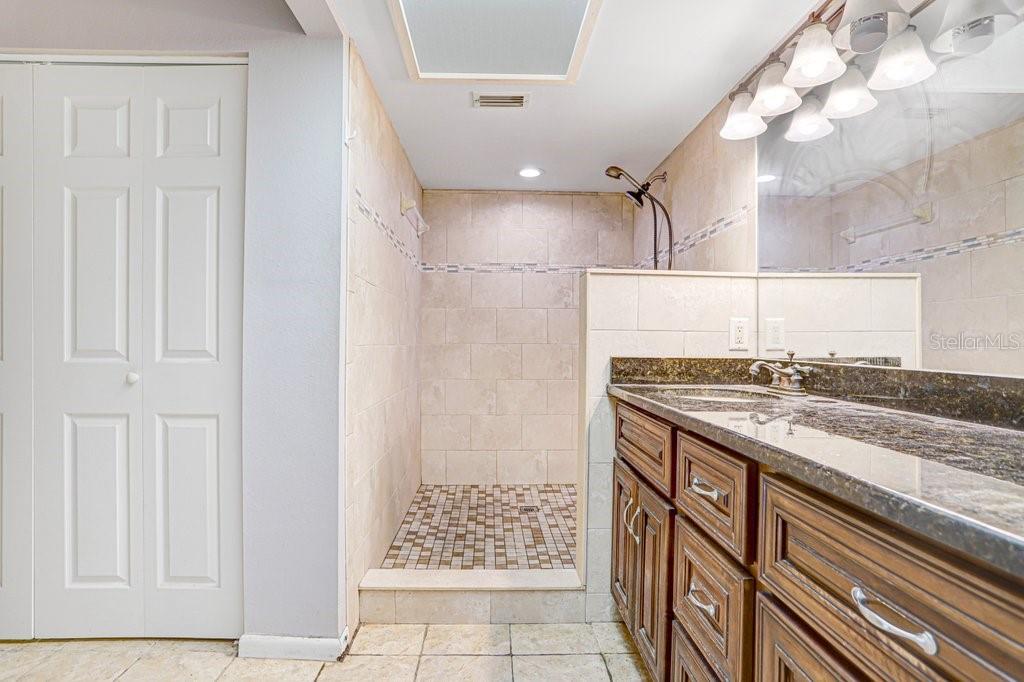 A bathroom features a tiled walk-in shower, a dark wood vanity, and a large mirror — 2025 SYLVESTER ROAD UNIT C2, LAKELAND, FL