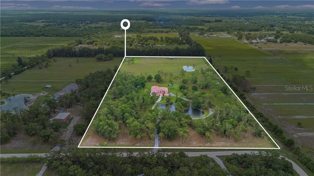 An aerial view shows a house with a pink roof on a large, wooded lot — 10750 146TH AVENUE, FELLSMERE, FL
