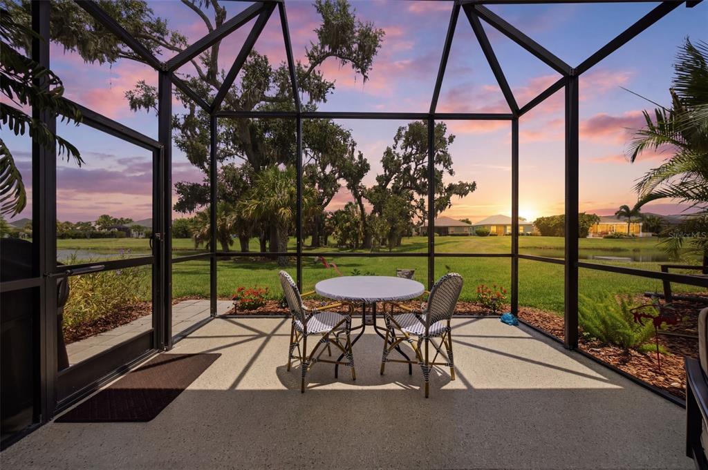 A screened-in patio with a table and chairs overlooks a grassy lawn and a pond — 4028 WILDGRASS PLACE, PARRISH, FL