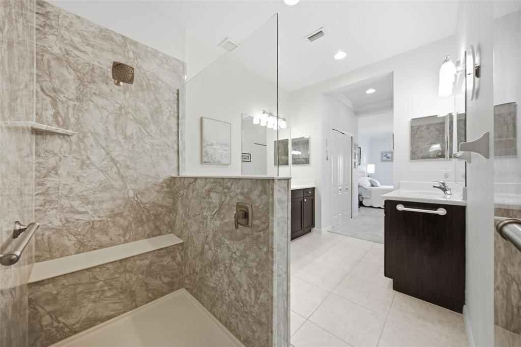 A bathroom features a walk-in shower with marble-look tile, a glass partition, and dark wood vanities — 4028 WILDGRASS PLACE, PARRISH, FL