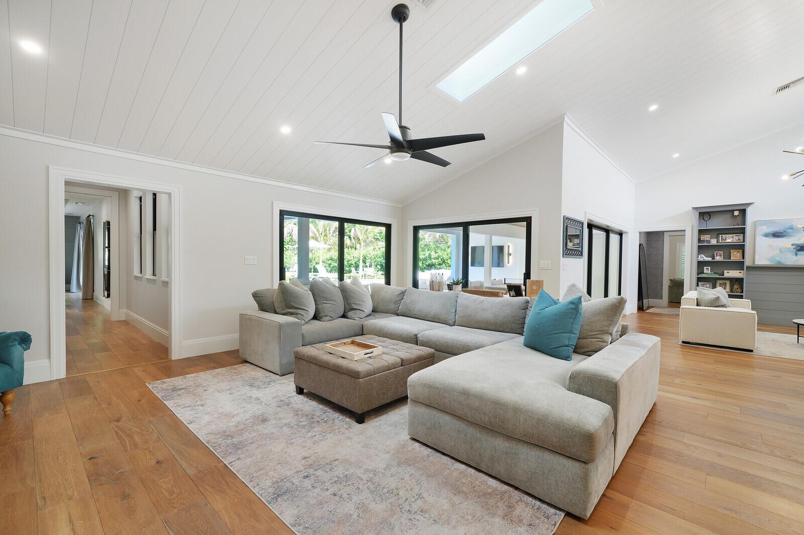 A spacious living room features a large sectional sofa, hardwood floors, and a vaulted ceiling — 19526 W Trails End Terrace, Jupiter FL 33458, JUPITER, FL