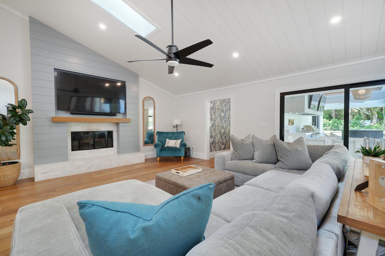 A living room features a vaulted ceiling, a shiplap fireplace, and a large sectional sofa — 19526 W Trails End Terrace, Jupiter FL 33458, JUPITER, FL