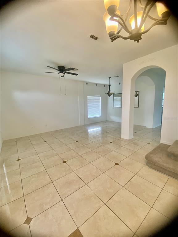 An open-concept living area features light-colored tile flooring, a ceiling fan, and an arched entryway — 1690 BIG OAK LANE, KISSIMMEE, FL