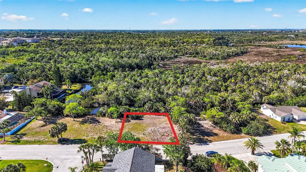 An aerial view shows a vacant rectangular lot outlined in red near a wooded area — 5804 SEABREEZE DRIVE, PORT RICHEY, FL