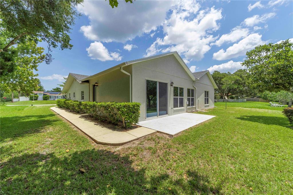The exterior of a house features a concrete patio, a walkway, and a manicured lawn — 10 BLYTH PLACE, PALM COAST, FL
