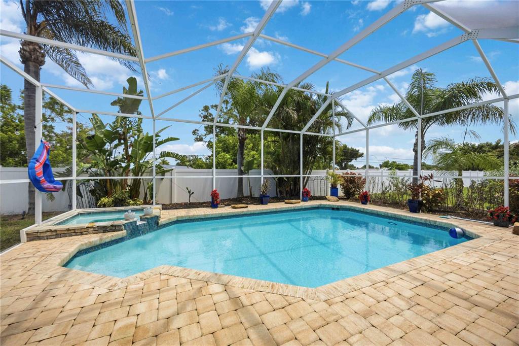 A screened-in swimming pool and spa with a brick paver deck and tropical landscaping — 4251 TENNYSON WAY, VENICE, FL