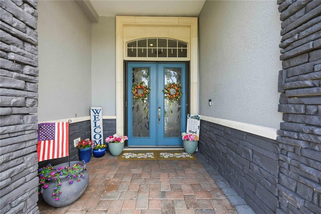 A blue double front door with glass inserts sits under a transom window on a porch — 4251 TENNYSON WAY, VENICE, FL