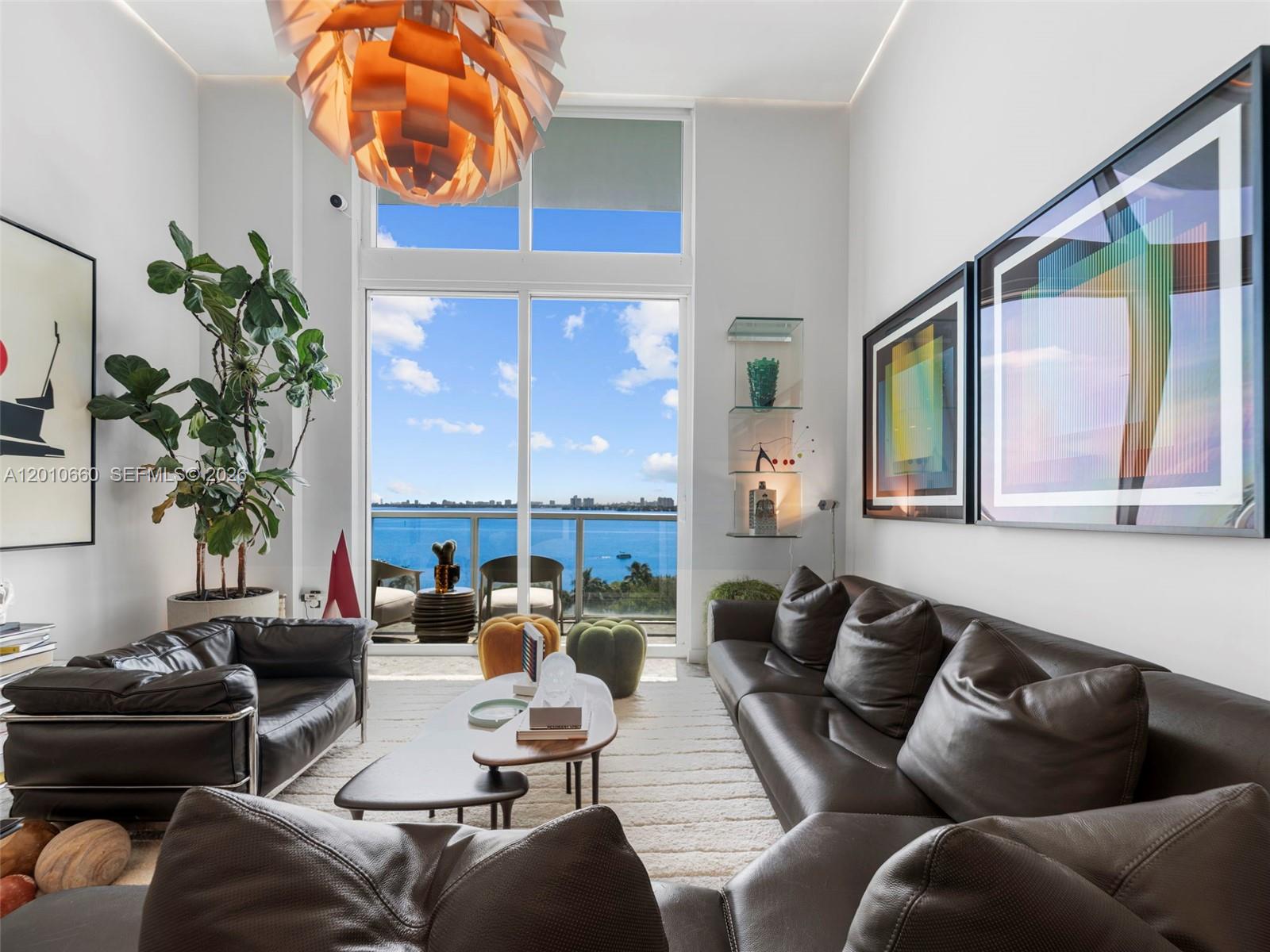 A modern living room features dark leather sofas, a sculptural light fixture, and floor-to-ceiling windows — 1900 N Bayshore Dr # 903, Miami FL 33132, MIAMI, FL