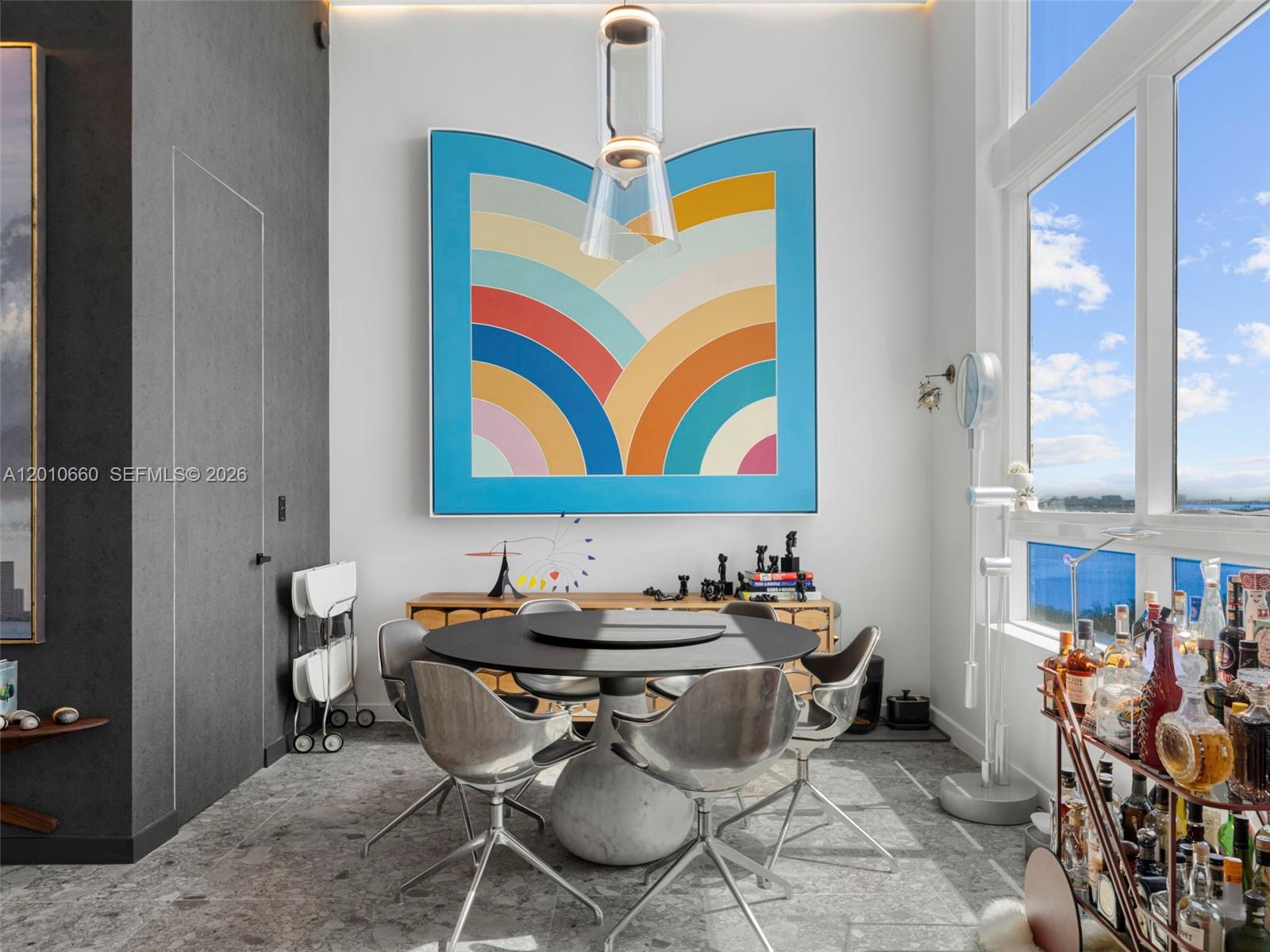 A dining room features a round table, metallic chairs, and a large colorful abstract painting — 1900 N Bayshore Dr # 903, Miami FL 33132, MIAMI, FL