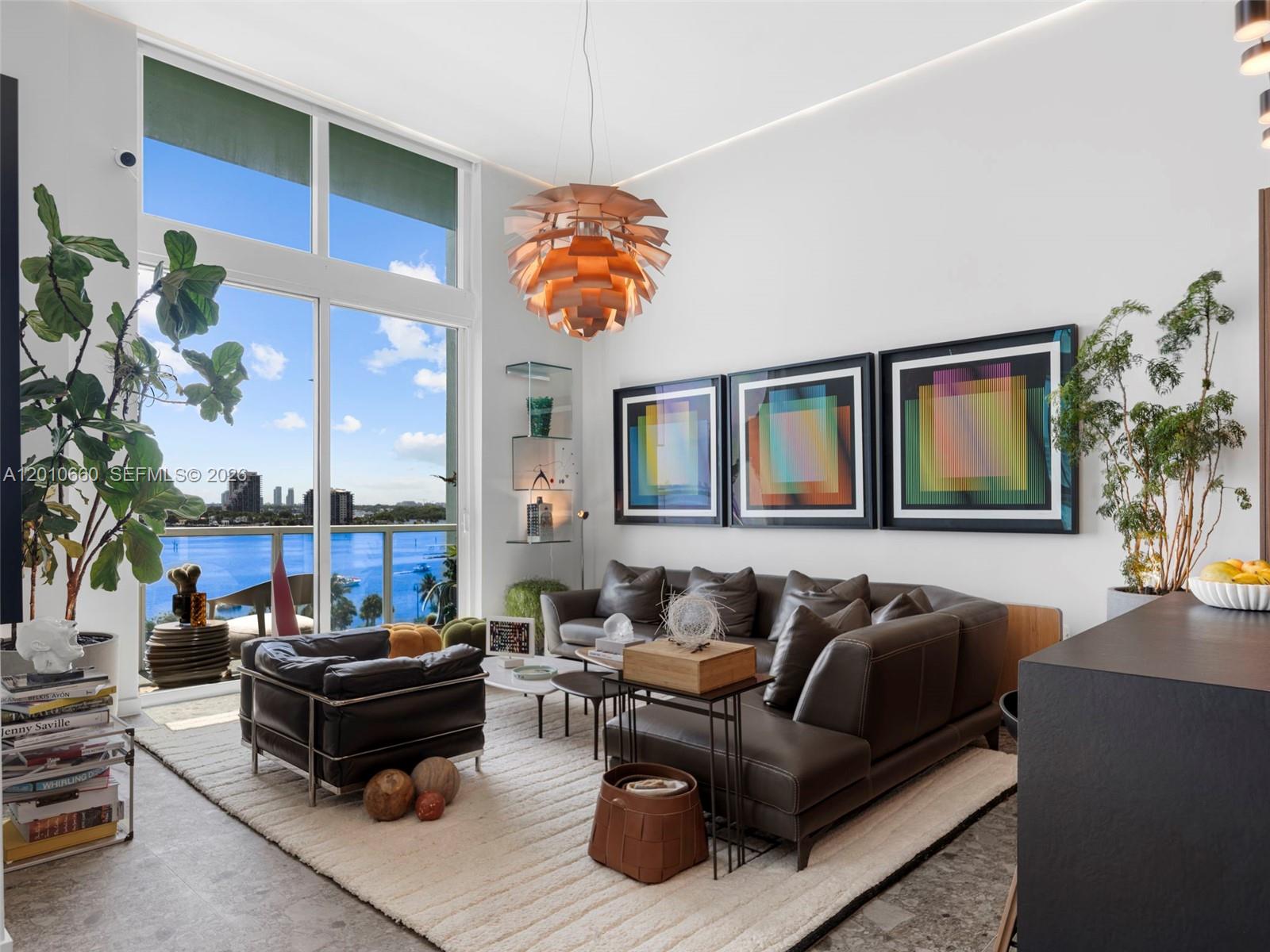 A modern living room features a large sectional, leather armchair, pendant light, and floor-to-ceiling windows — 1900 N Bayshore Dr # 903, Miami FL 33132, MIAMI, FL
