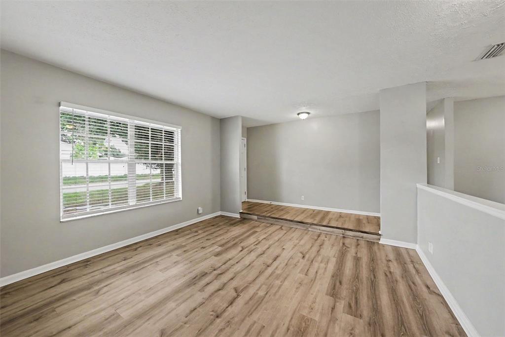 An empty room features light gray walls, wood-look flooring, and a small raised platform area — 2264 VILLAGE COURT, BRANDON, FL