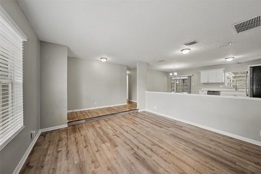 A living room with wood-look flooring features a raised dining area and an open kitchen — 2264 VILLAGE COURT, BRANDON, FL