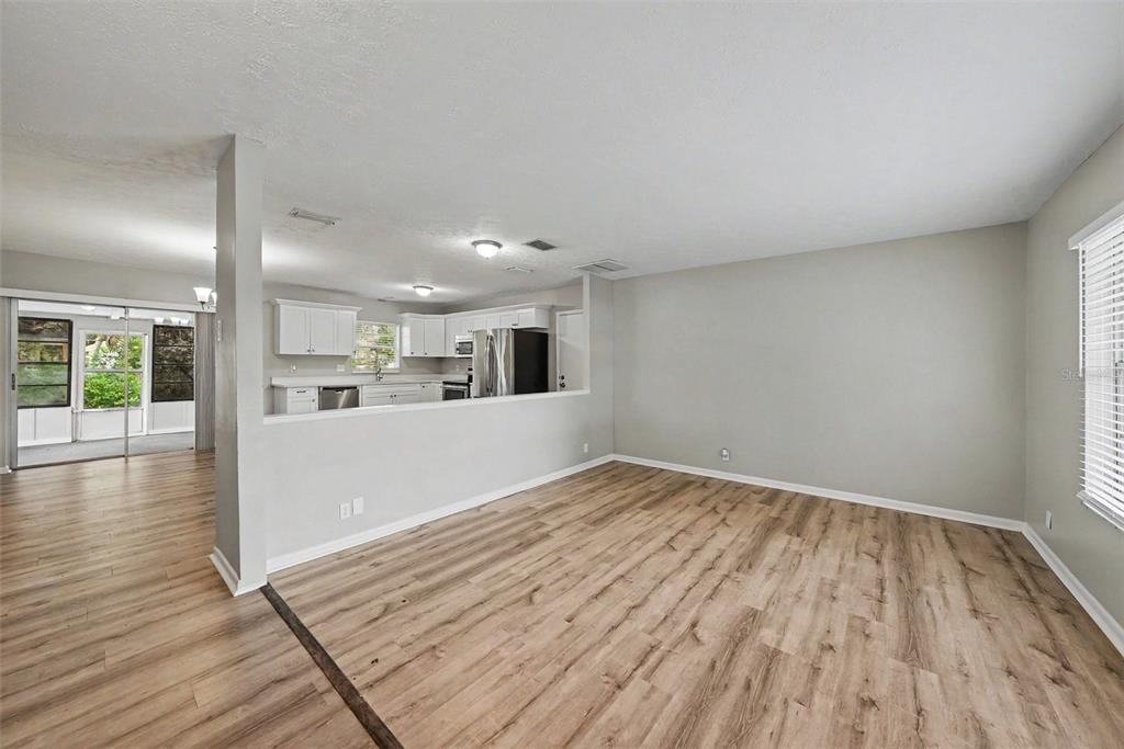 An open-concept living room features light wood-look flooring and a view into the kitchen — 2264 VILLAGE COURT, BRANDON, FL