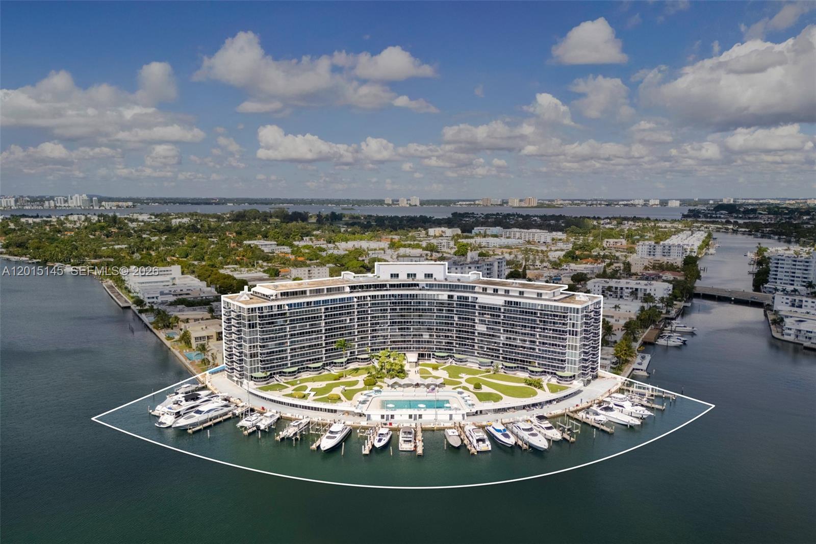 Aerial view of a curved waterfront residential building with a pool and private boat slips — 900 Bay Dr DS14, Miami Beach FL 33141, MIAMI BEACH, FL
