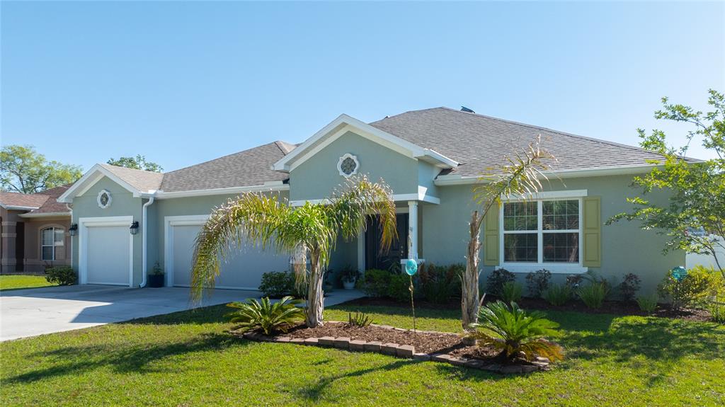 A single-story house with a light green exterior, a two-car garage, and a palm tree — 17 WHITE HAVEN LANE, PALM COAST, FL