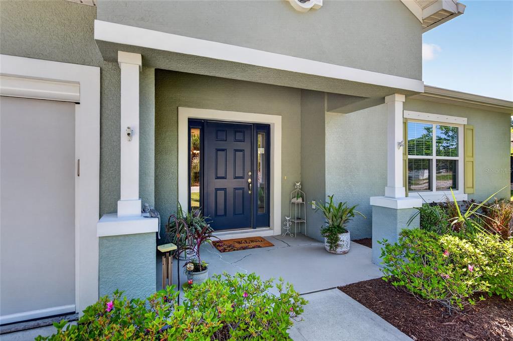 A covered front porch features a dark blue front door and a concrete walkway — 17 WHITE HAVEN LANE, PALM COAST, FL