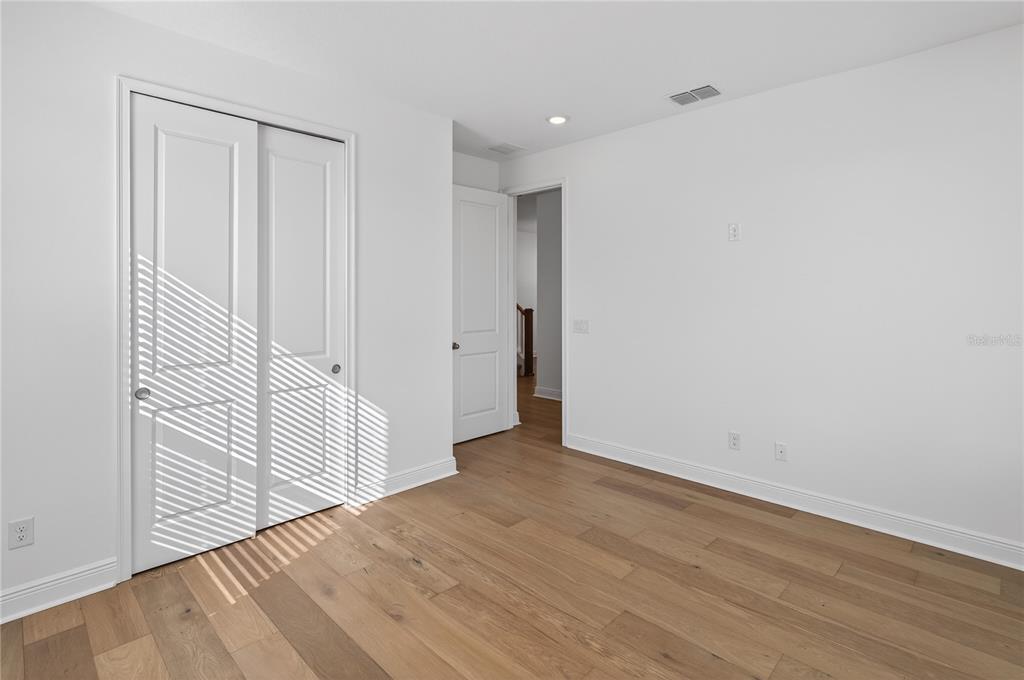 An empty bedroom features white walls, light wood flooring, and a white sliding closet door — 2926 SAILHOUSE DRIVE, ST CLOUD, FL