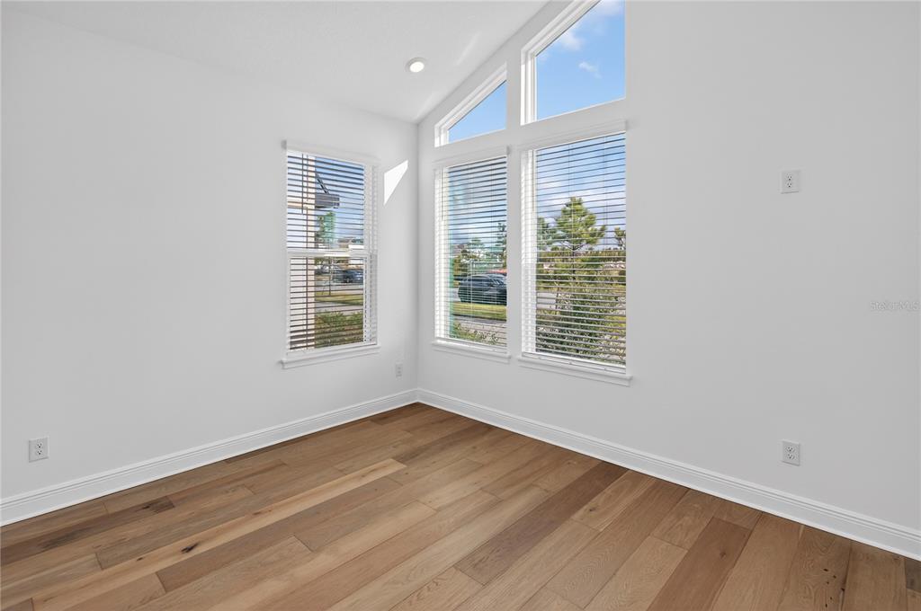 An empty room with white walls, light wood flooring, and tall windows with blinds — 2926 SAILHOUSE DRIVE, ST CLOUD, FL