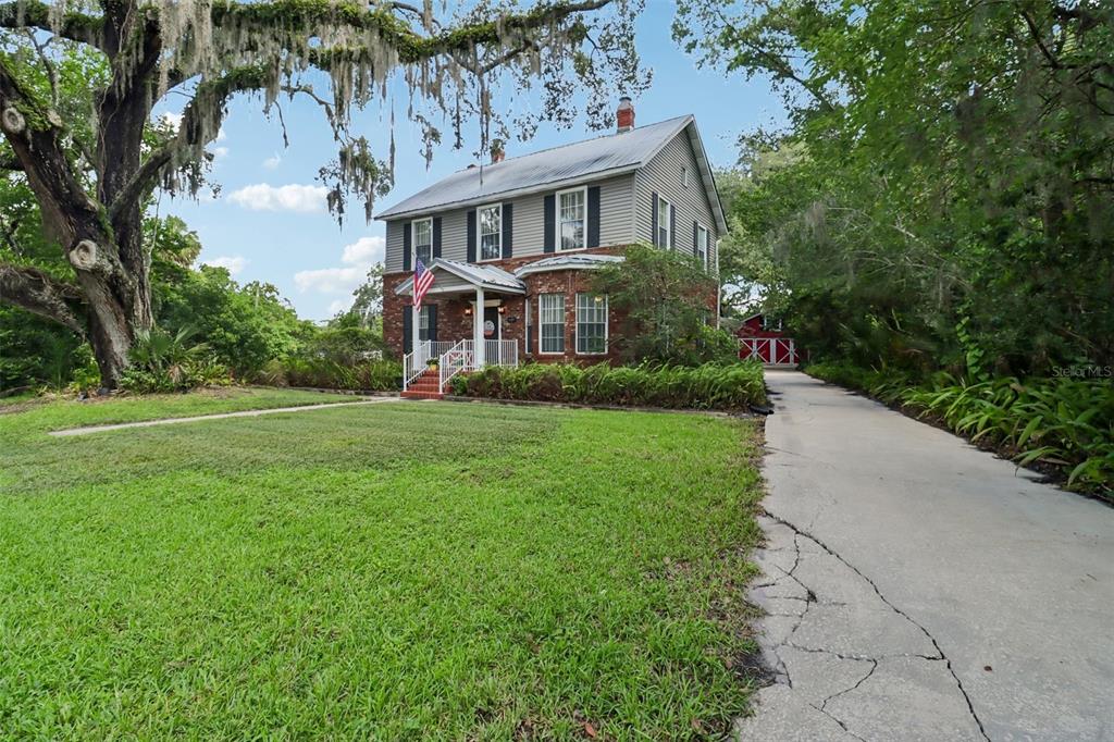 A two-story house with a brick and gray siding exterior sits beside a long driveway — 649 GLENWAY DRIVE, SANFORD, FL