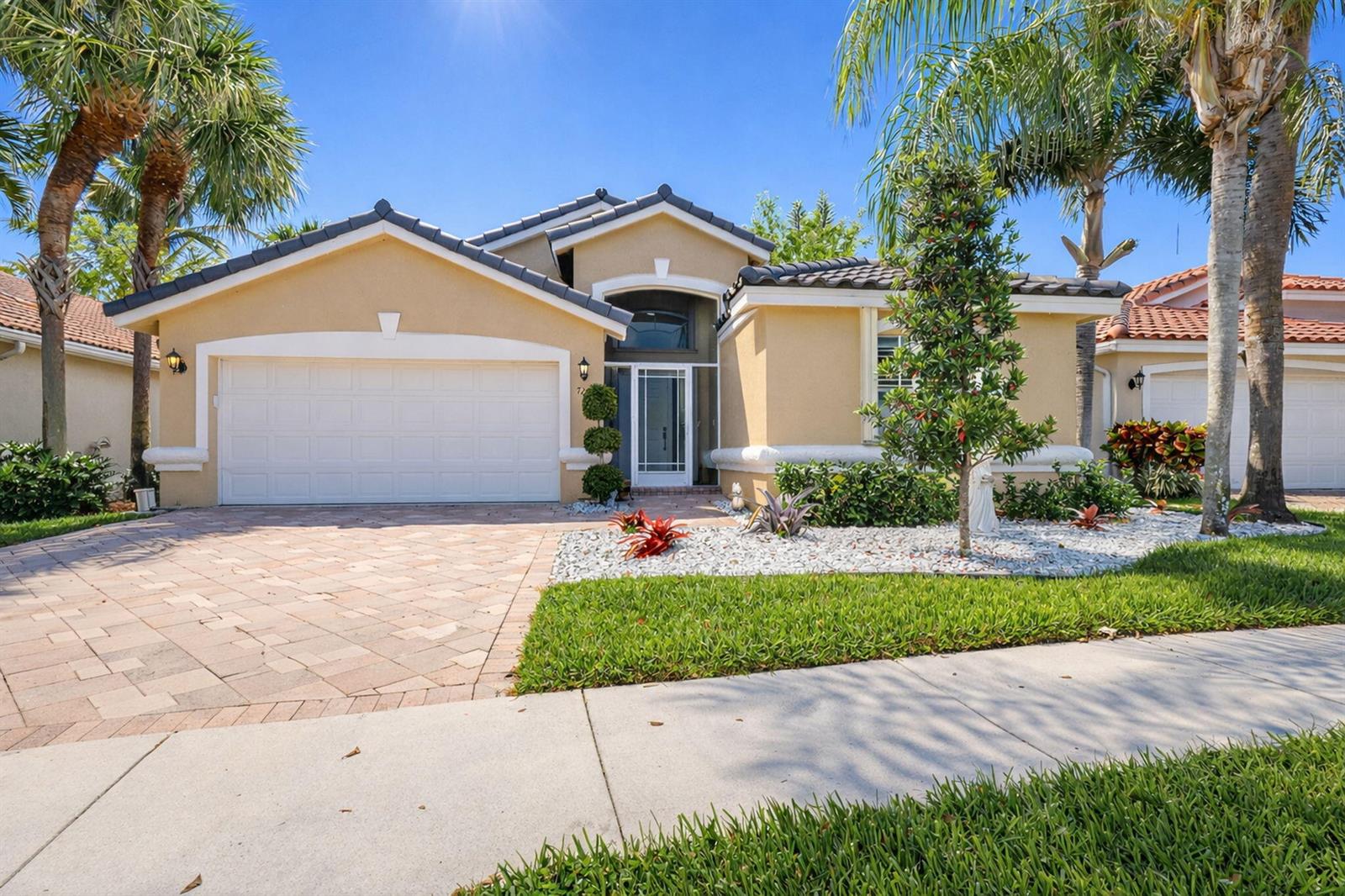 A single-story tan house with a tiled roof, paver driveway, and palm trees — 7207 Modena Drive, Boynton Beach FL 33437, BOYNTON BEACH, FL