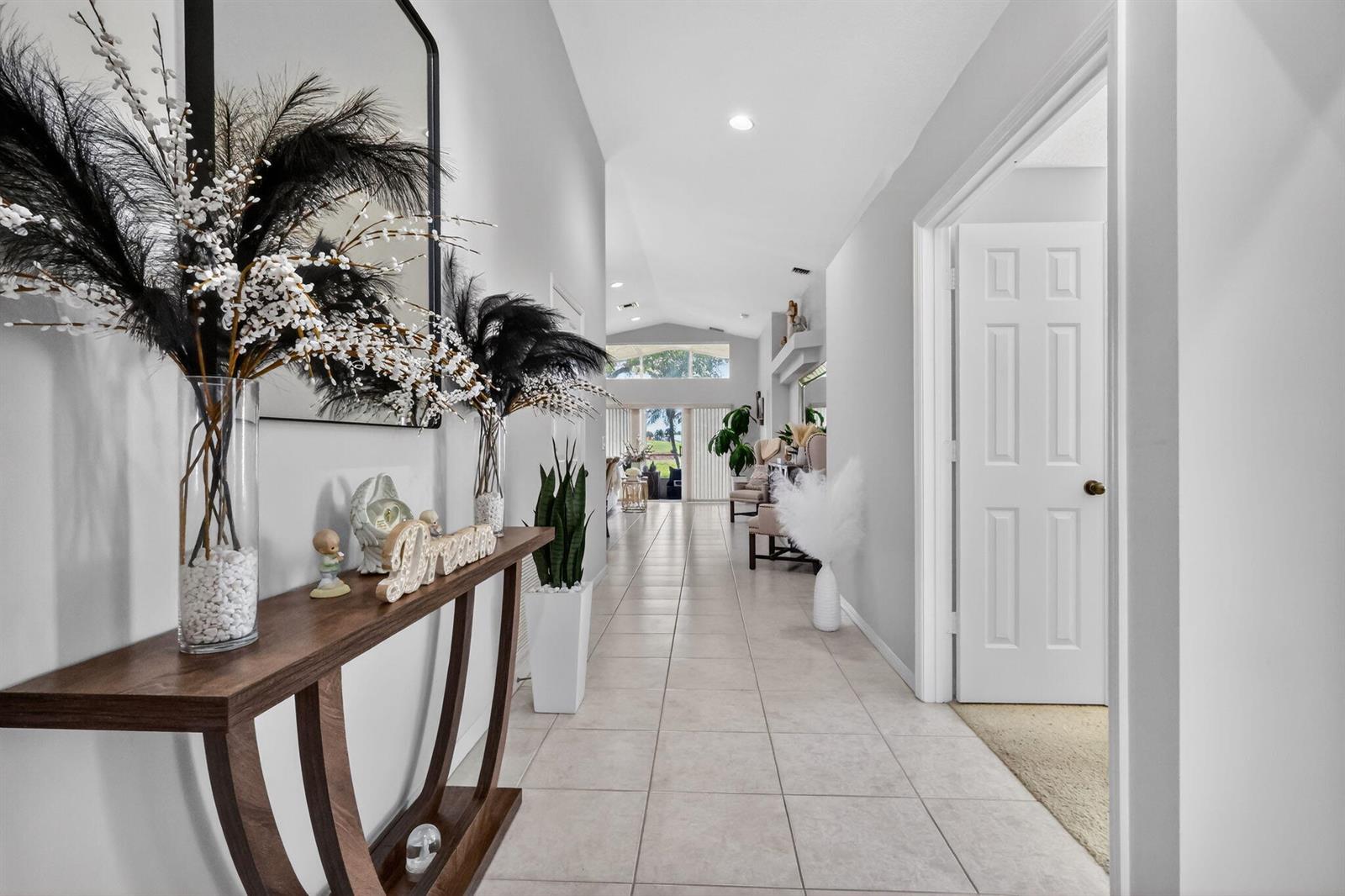 A tiled hallway leads from a console table toward a bright, open living area — 7207 Modena Drive, Boynton Beach FL 33437, BOYNTON BEACH, FL