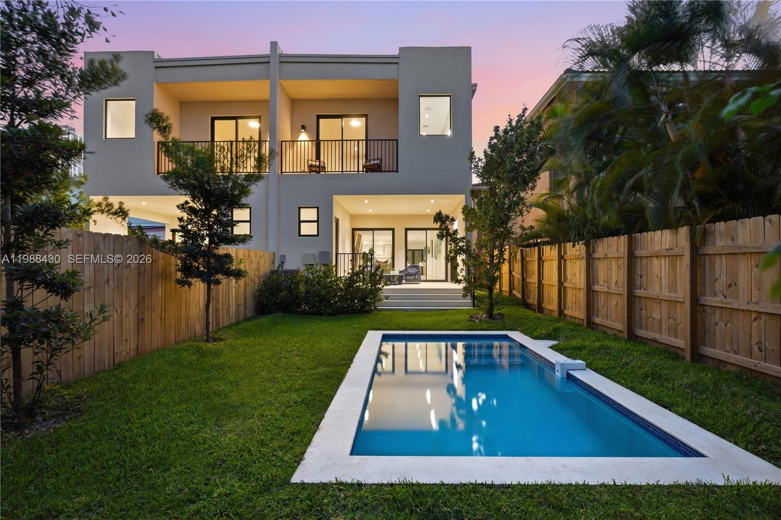 A two-story house with a backyard swimming pool and a wooden fence at dusk — 2925 SW 36th Ave, Miami FL 33133, MIAMI, FL
