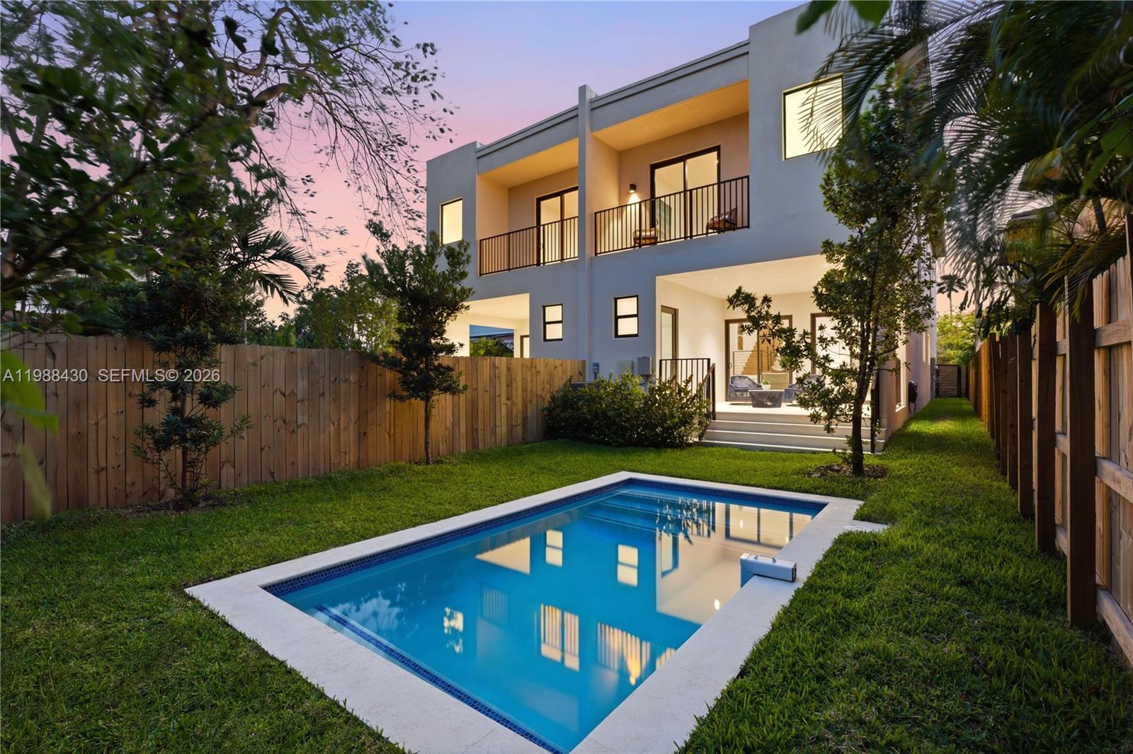 A two-story modern house with a backyard pool and wooden privacy fencing at dusk — 2925 SW 36th Ave, Miami FL 33133, MIAMI, FL