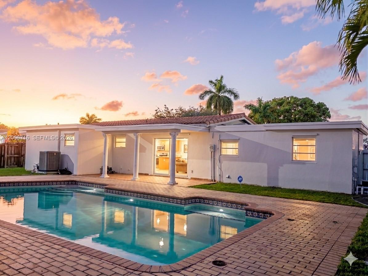 A backyard view of a white house with a swimming pool and brick patio — 3831 E 10th Ave, Hialeah FL 33013, HIALEAH, FL