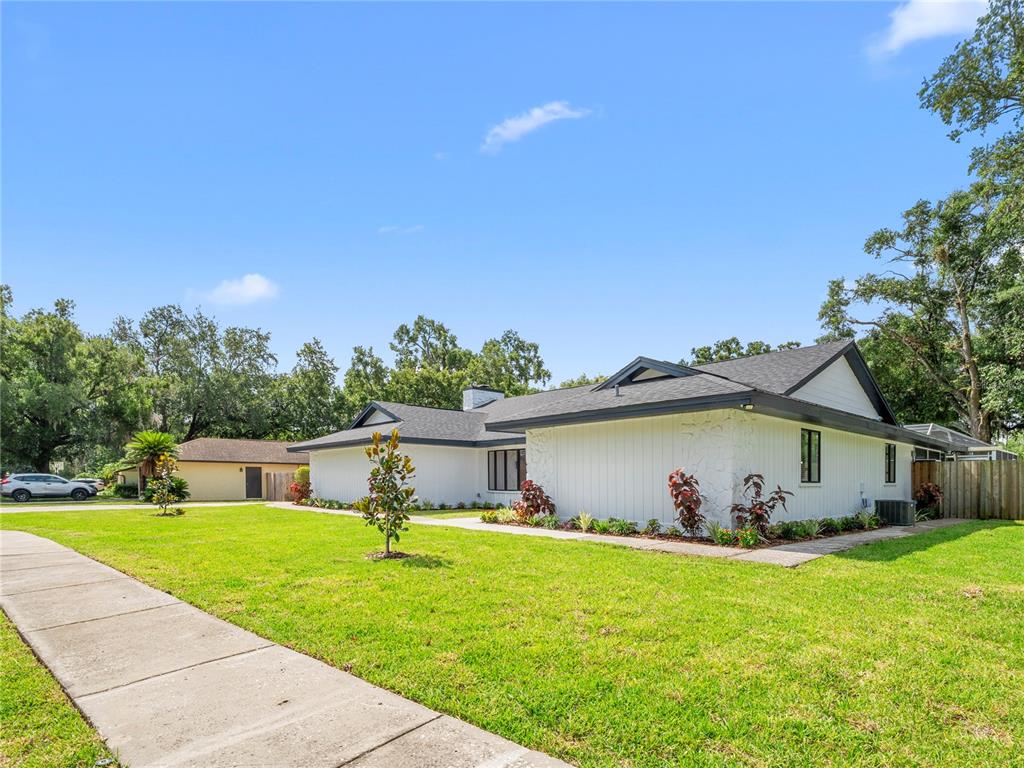 A white, single-story house with a dark roof sits on a grassy lot — 15901 DOVER CLIFFE DRIVE, LUTZ, FL