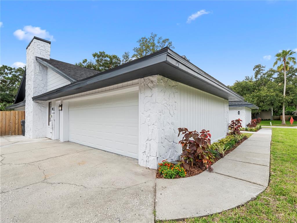 A white house with a stone chimney and a two-car garage under a blue sky — 15901 DOVER CLIFFE DRIVE, LUTZ, FL