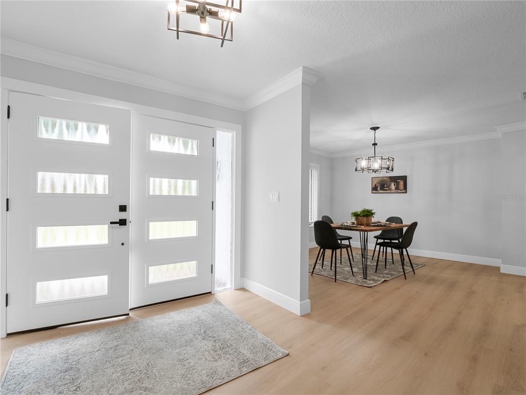 An entryway with a white front door leads to a dining room with wood flooring — 15901 DOVER CLIFFE DRIVE, LUTZ, FL