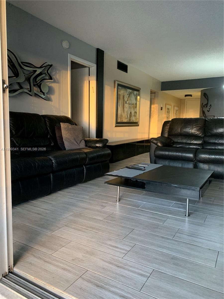 A living room features two black leather sofas, a coffee table, and light wood-look flooring — 4025 N Nob Hill Rd # 508, Sunrise FL 33351, SUNRISE, FL