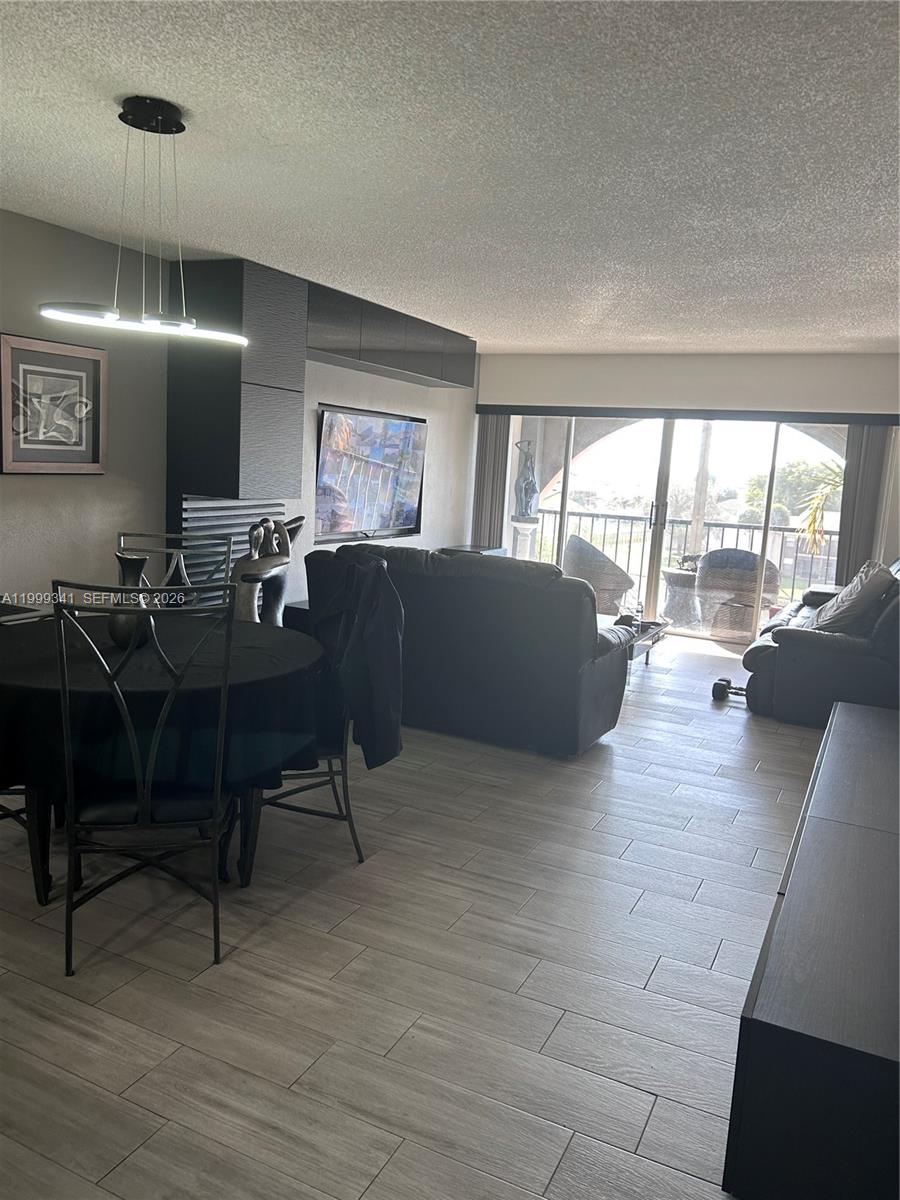A living and dining area features dark furniture, wood-look tile flooring, and a sliding glass door — 4025 N Nob Hill Rd # 508, Sunrise FL 33351, SUNRISE, FL
