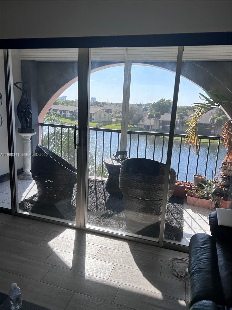 A balcony with wicker chairs and a water view is visible through sliding glass doors — 4025 N Nob Hill Rd # 508, Sunrise FL 33351, SUNRISE, FL