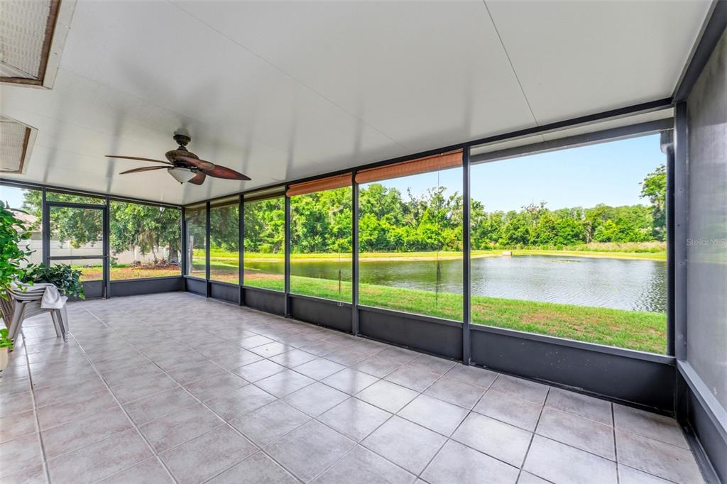 A tiled screened-in porch overlooks a pond and a line of trees — 9847 EDMONTON DRIVE, LAND O LAKES, FL