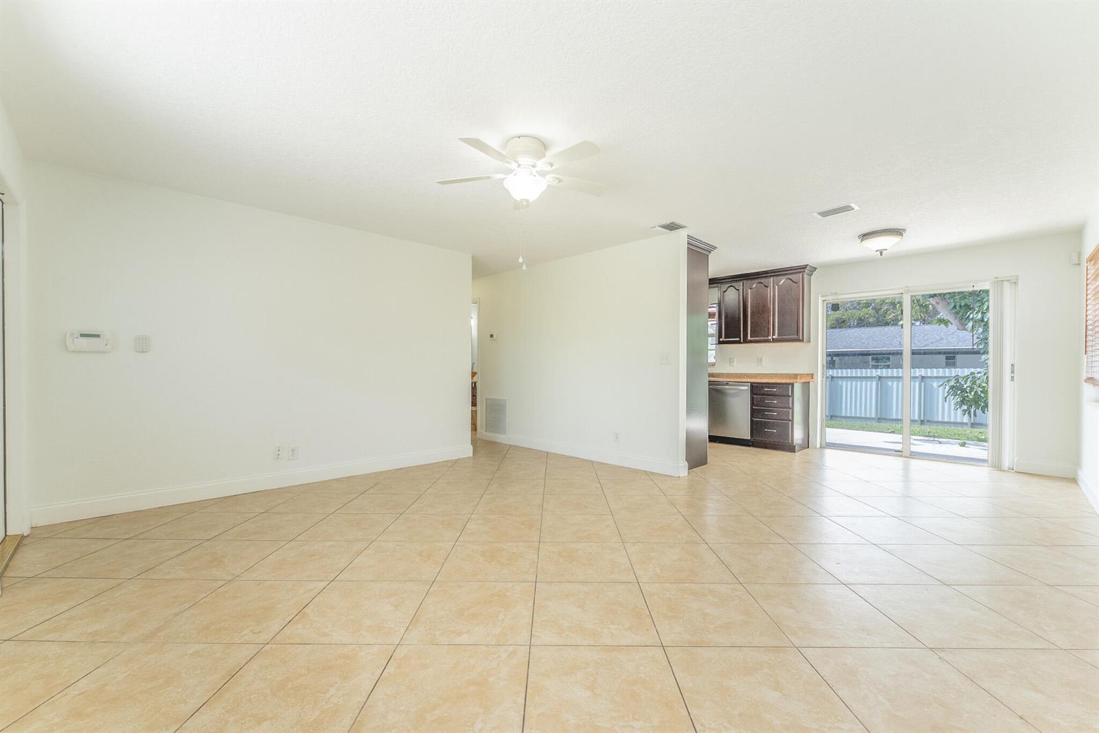 An open-concept living area features light-colored tile flooring, white walls, and a kitchen with dark cabinets — 63 Andros Road, Palm Springs FL 33461, PALM SPRINGS, FL