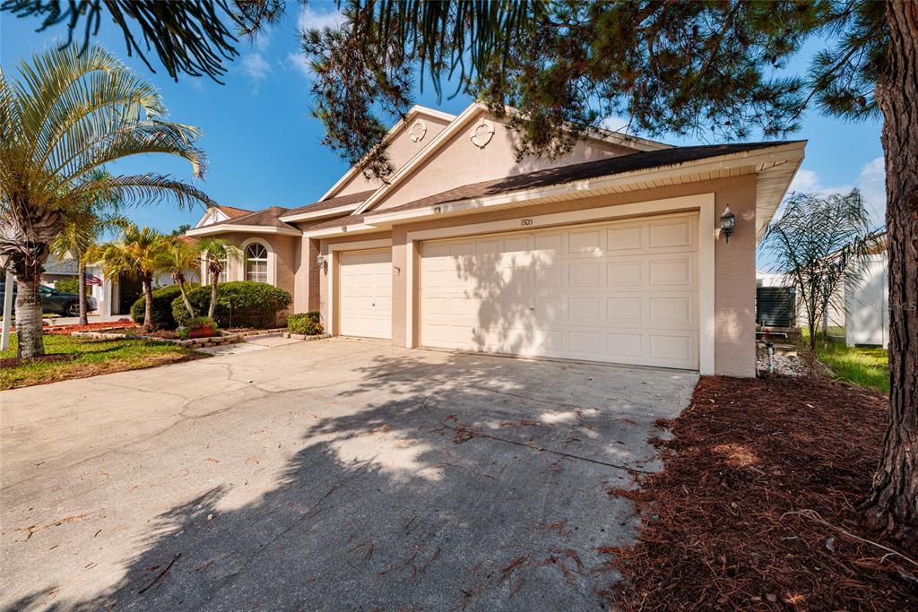 A bathroom features a double vanity with a stone countertop, a soaking tub, and tile flooring — 1805 WOOD BEND STREET, TARPON SPRINGS, FL