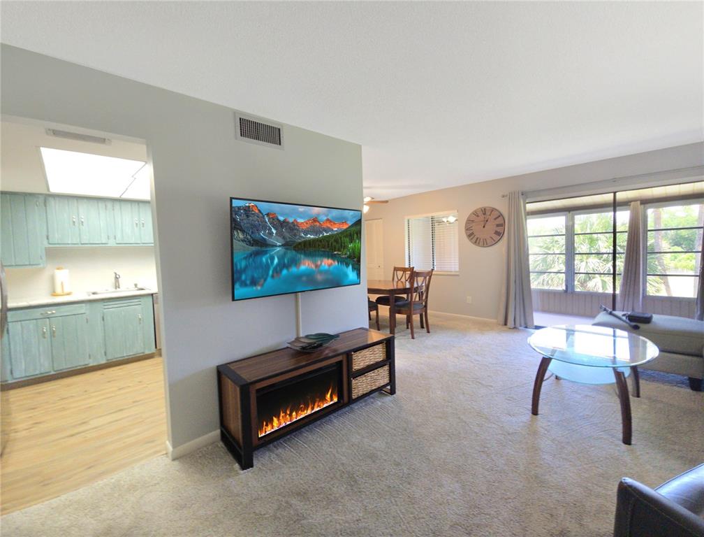 A living room with a wall-mounted television, fireplace console, and an adjacent kitchen — 648 MIDWAY DRIVE UNIT B, OCALA, FL