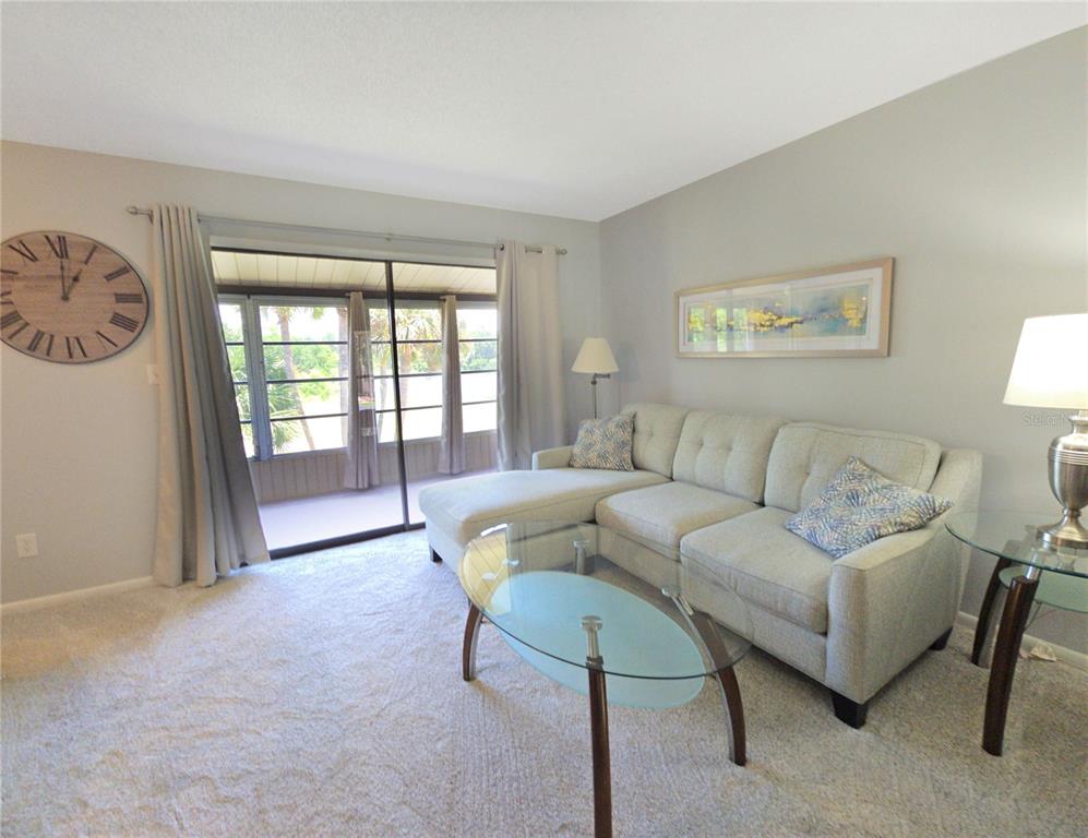 A living room features a light-colored sectional sofa, a glass coffee table, and sliding glass doors — 648 MIDWAY DRIVE UNIT B, OCALA, FL