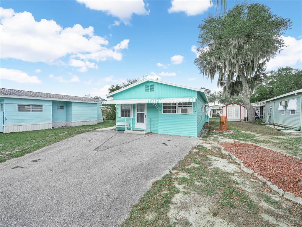 A turquoise mobile home with a paved driveway and a large oak tree nearby — 8 SILVER DOCTOR LANE, LAKE WALES, FL