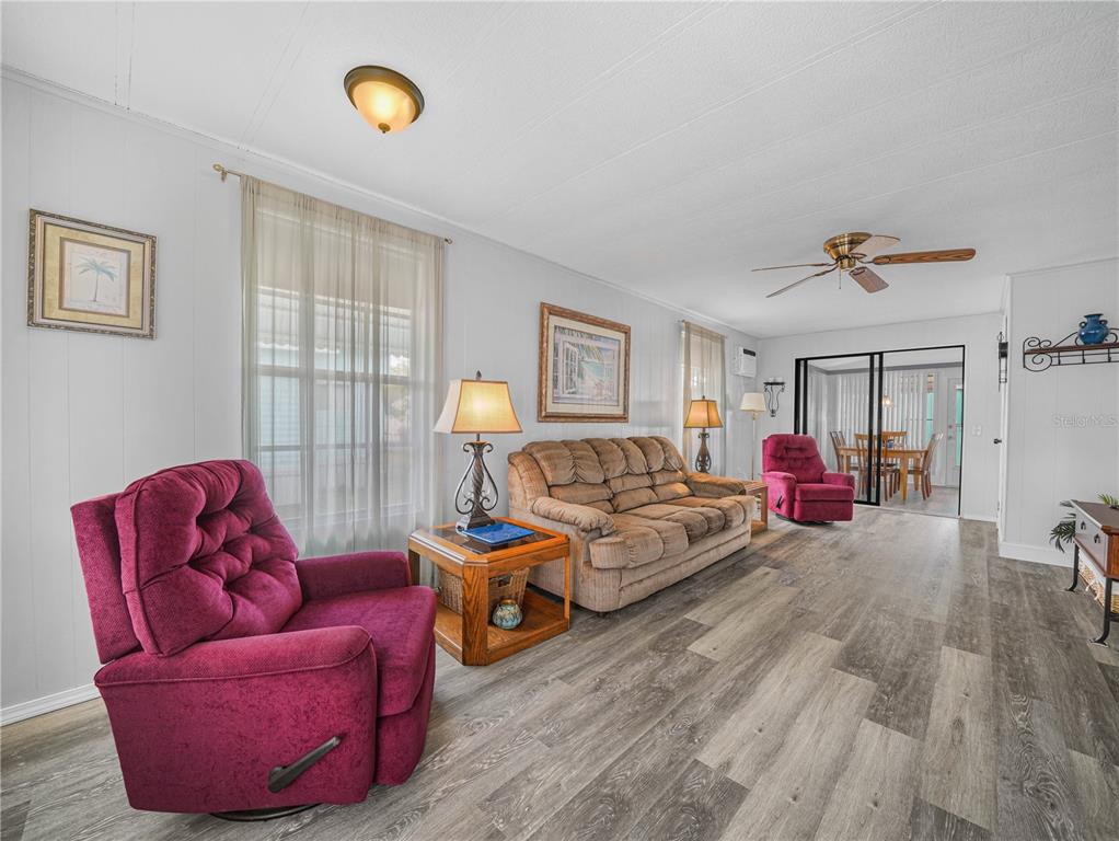 A living room features wood-look flooring, a tan sofa, and two magenta recliners — 8 SILVER DOCTOR LANE, LAKE WALES, FL
