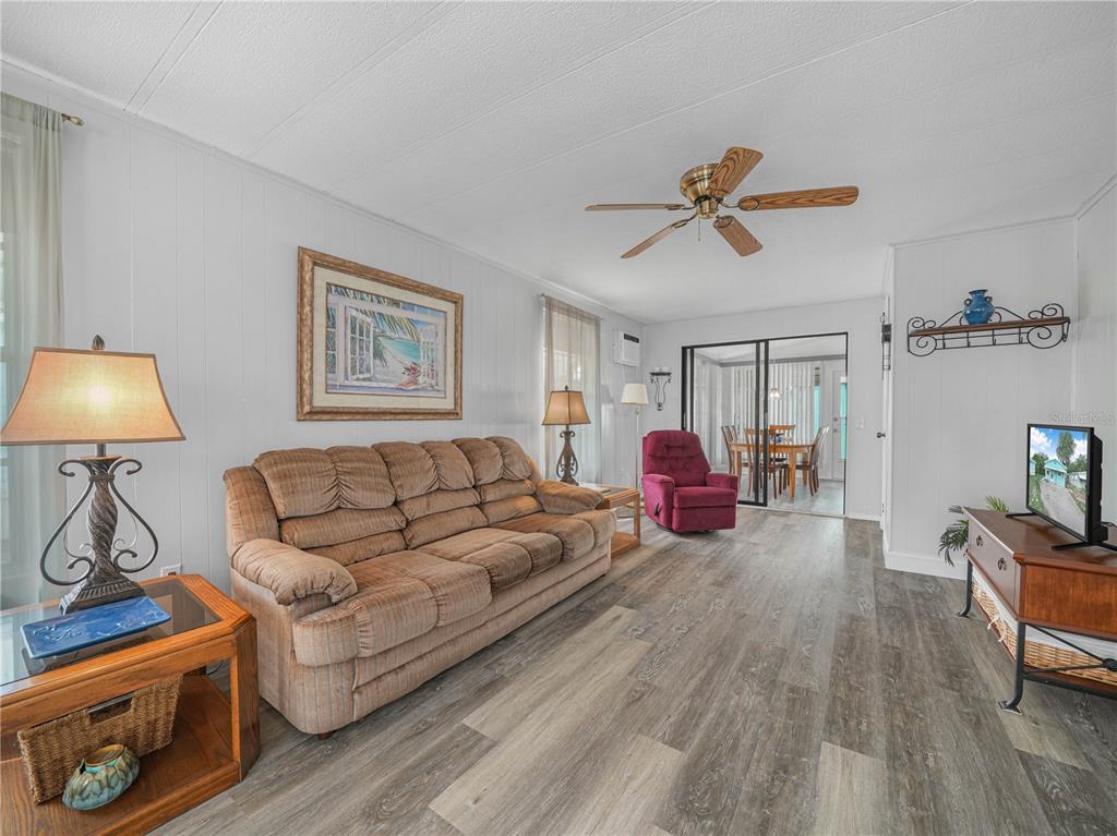 A living room features wood-look flooring, a brown sofa, a red recliner, and a ceiling fan — 8 SILVER DOCTOR LANE, LAKE WALES, FL