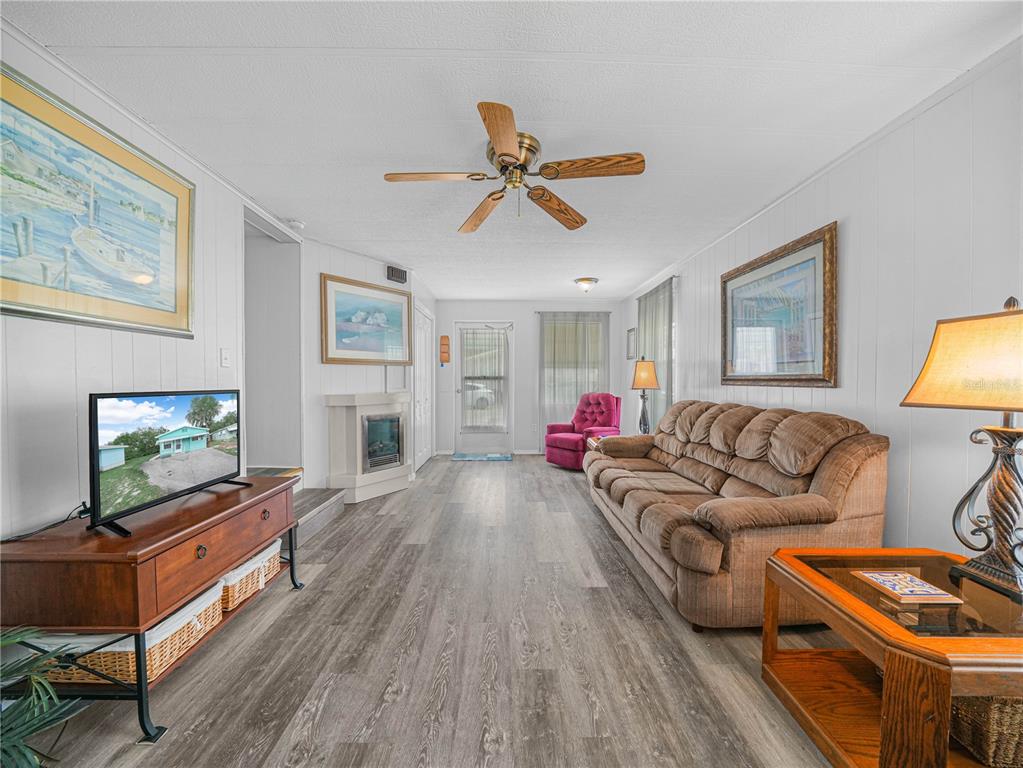 A living room features wood-look flooring, a brown sofa, a television, and a ceiling fan — 8 SILVER DOCTOR LANE, LAKE WALES, FL
