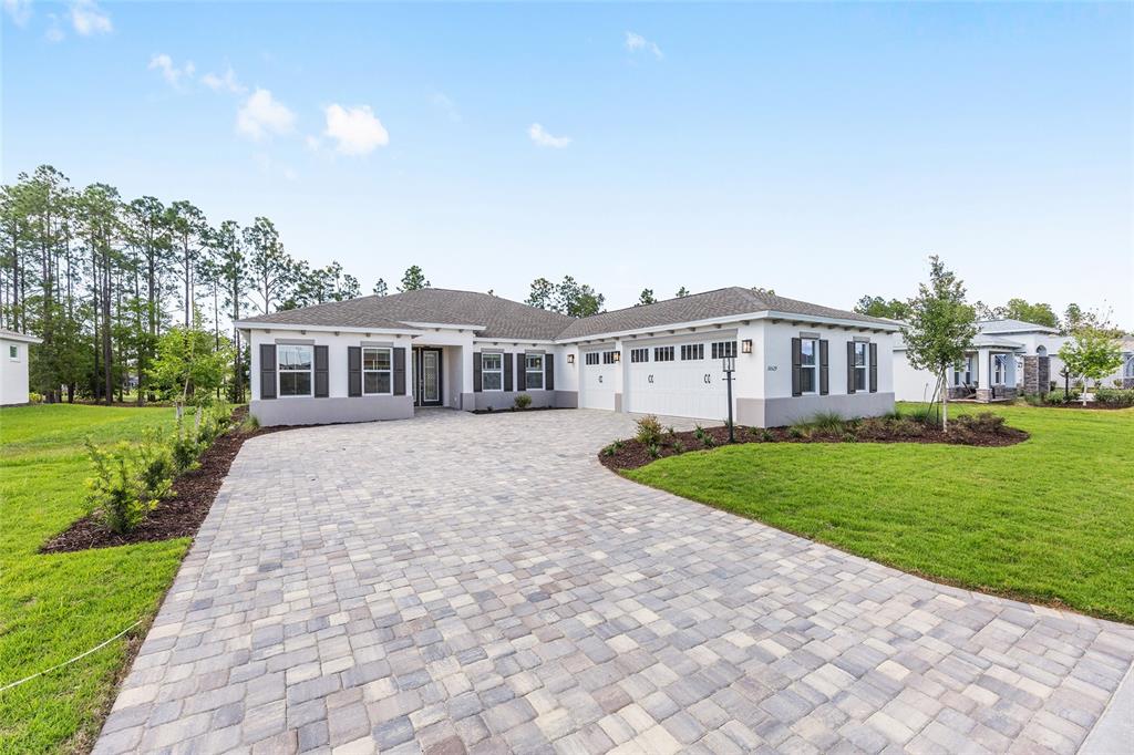 A single-story house with a paved driveway, three-car garage, and a light-colored stucco exterior — 10529 SW 96TH LANE ROAD, OCALA, FL