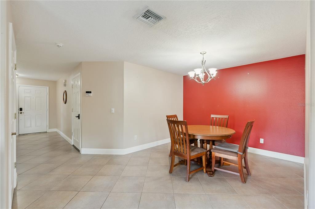 A dining area features a round wooden table, four chairs, and a red accent wall — 3527 CARUSO PLACE, OVIEDO, FL